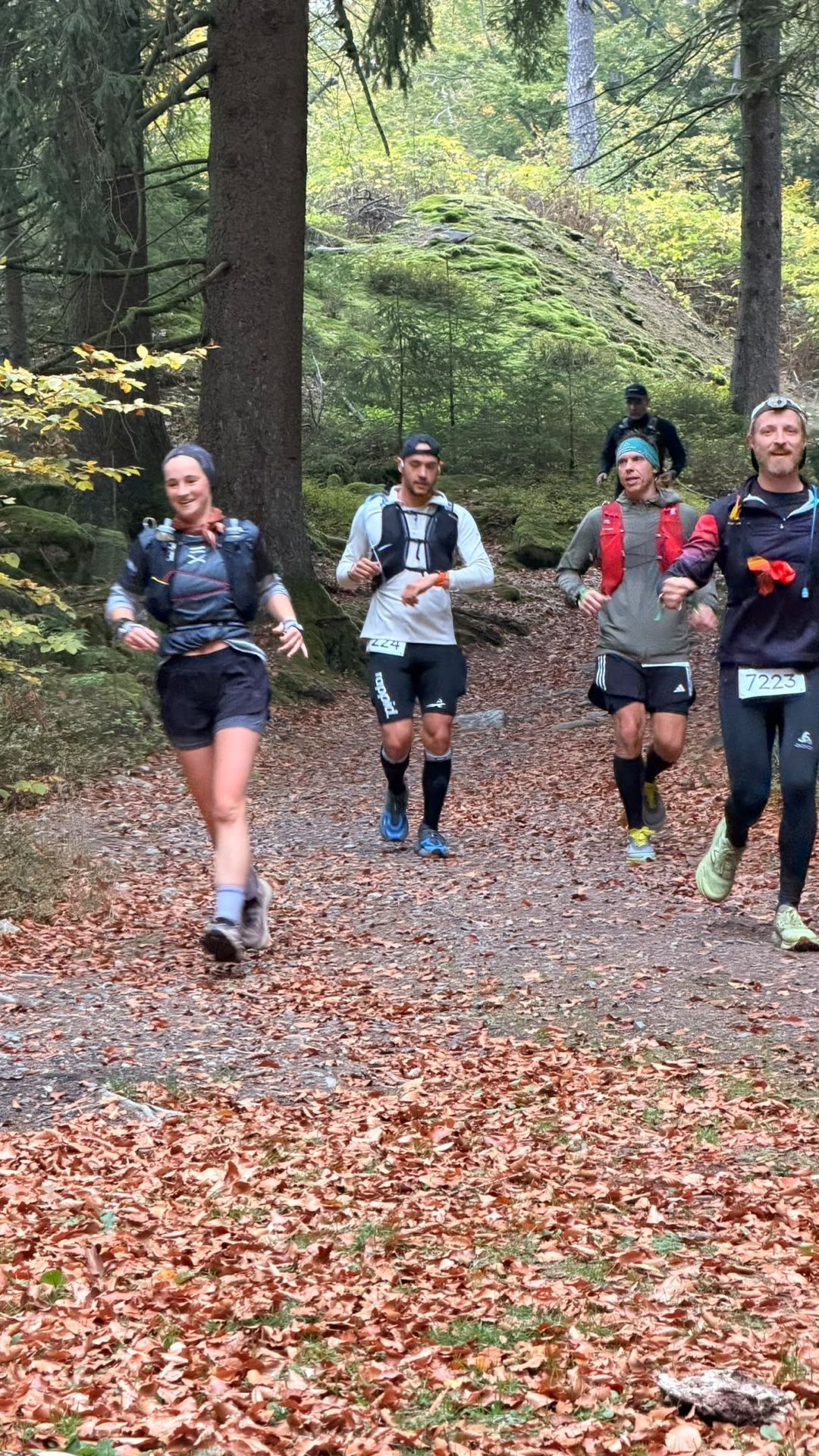 Eine Gruppe Trailläufer kommt auf einem laubbedeckten Waldweg entgegen, darunter Nick Alexej Wriedt mit Startnummer 224